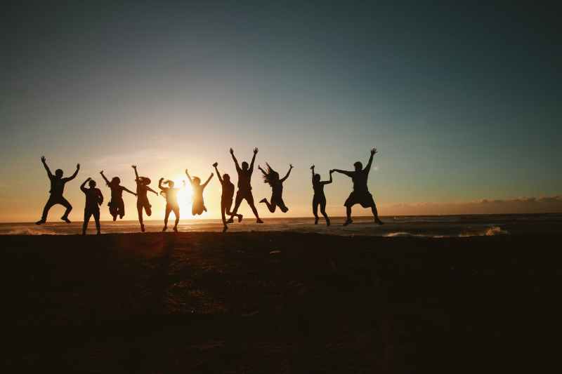 group jumping against sunset silhouette